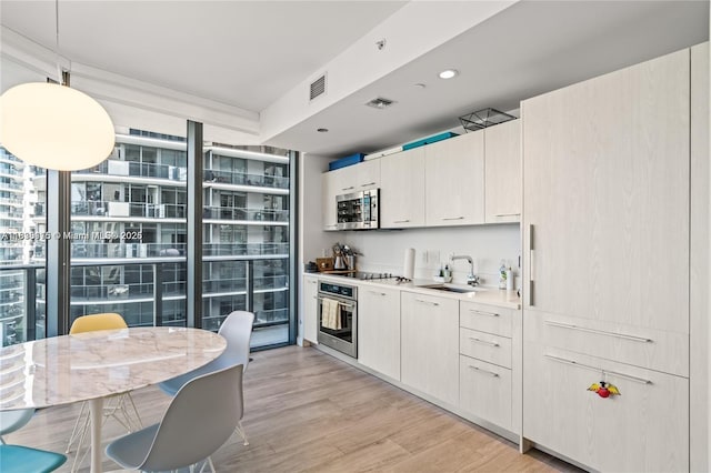 55 SW 9th St Unit 1801, Miami, FL 33130 - kitchen featuring stainless steel appliances, light wood-type flooring, light countertops, pendant lighting, and floor to ceiling windows