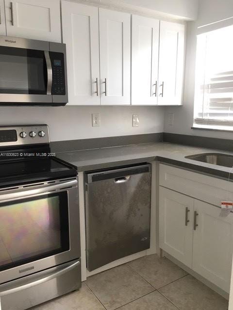 342 NW 84th Ter Unit 342, Miami, FL 33150 - kitchen with stainless steel appliances, light tile patterned floors, and white cabinets