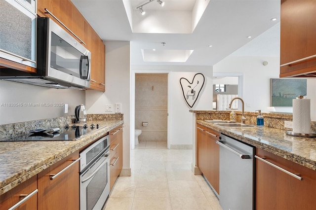 110 Washington Ave Unit 1608, Miami Beach, FL 33139 - kitchen featuring appliances with stainless steel finishes, a raised ceiling, brown cabinets, light stone counters, and light tile patterned floors