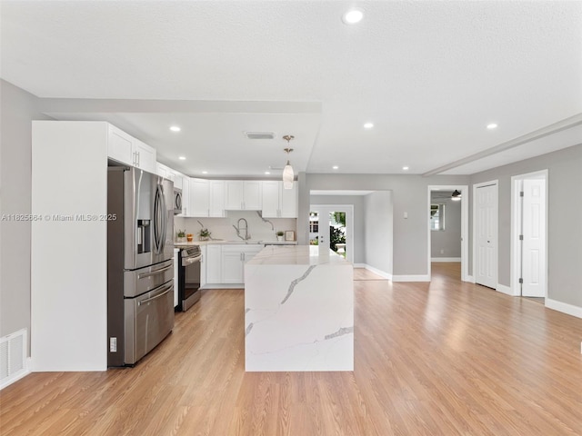2991 NW 1st Dr, Pompano Beach, FL 33064 - kitchen featuring appliances with stainless steel finishes, light stone counters, white cabinets, light wood-style floors, and recessed lighting