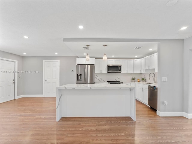2991 NW 1st Dr, Pompano Beach, FL 33064 - kitchen with stainless steel appliances, white cabinets, recessed lighting, light wood-style floors, and a center island