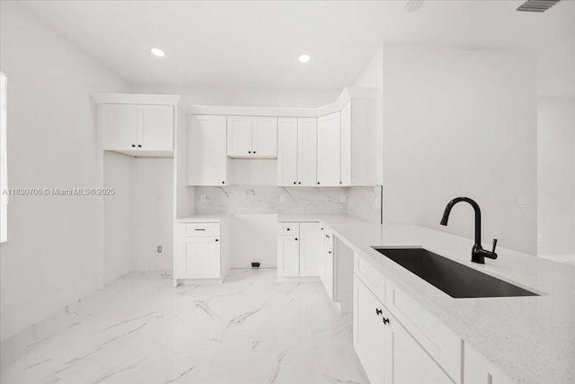 1212 Edelweiss St E, Lehigh Acres, FL 33974 - kitchen featuring light marble finish floors, recessed lighting, white cabinetry, decorative backsplash, and light stone counters