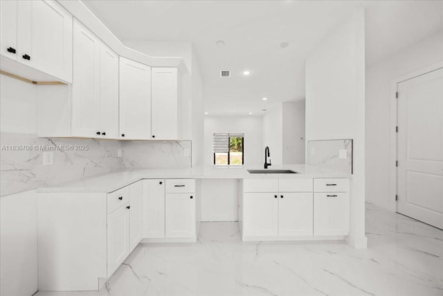 1212 Edelweiss St E, Lehigh Acres, FL 33974 - kitchen with light marble finish floors, backsplash, recessed lighting, white cabinetry, and light countertops