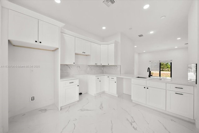 1212 Edelweiss St E, Lehigh Acres, FL 33974 - kitchen with recessed lighting, light marble finish flooring, white cabinets, and backsplash