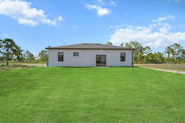 1212 Edelweiss St E, Lehigh Acres, FL 33974 - back of house with stucco siding and a lawn