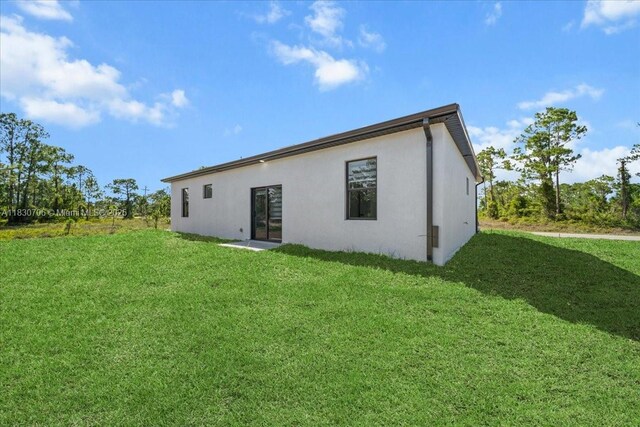 1212 Edelweiss St E, Lehigh Acres, FL 33974 - rear view of house featuring stucco siding and a yard