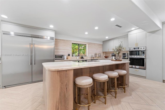 15202 SW 80th Ave, Palmetto Bay, FL 33157 - kitchen with appliances with stainless steel finishes, a kitchen island, decorative backsplash, a breakfast bar area, and recessed lighting
