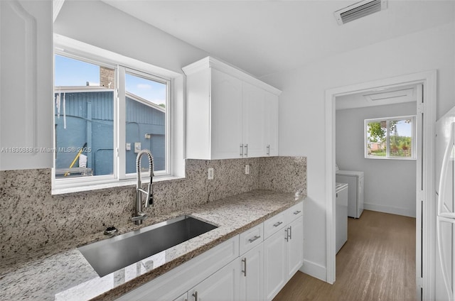 11504 SW 226th St, Miami, FL 33170 - kitchen featuring washer and dryer, white cabinetry, decorative backsplash, wood finished floors, and light stone countertops