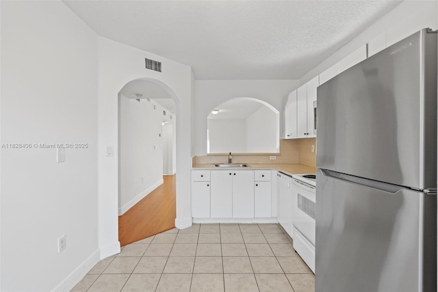 945 NE 34th Ave Unit 103, Homestead, FL 33033 - kitchen with freestanding refrigerator, light countertops, white electric stove, white cabinetry, and light tile patterned floors