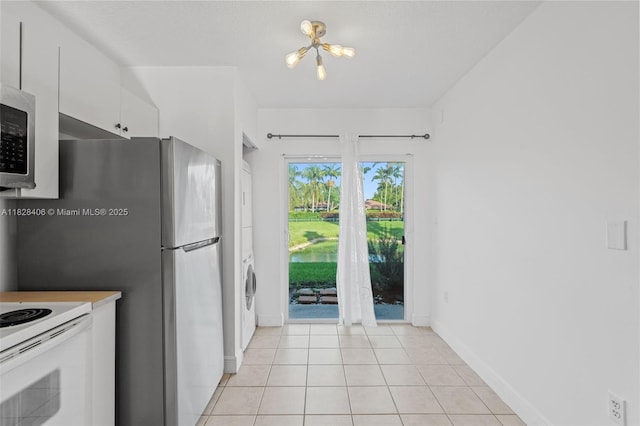 945 NE 34th Ave Unit 103, Homestead, FL 33033 - kitchen featuring white cabinets, stainless steel microwave, light tile patterned floors, a chandelier, and white electric range