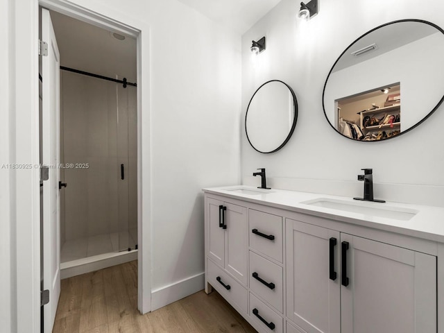 14913 SW 143rd Ct, Miami, FL 33186 - bathroom featuring wood finished floors, double vanity, a shower stall, and a spacious closet