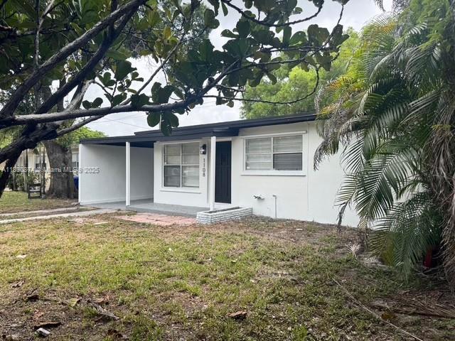 1108 SW 22nd Ave, Fort Lauderdale, FL 33312 - view of front of house with stucco siding, a front lawn, a carport, and covered porch