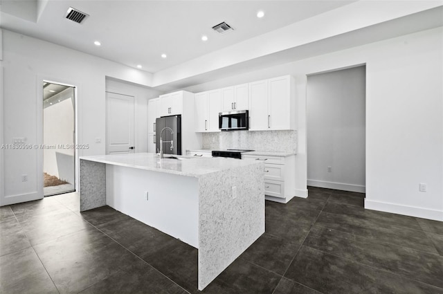 3324 NE 27, Naples, FL 34120 - kitchen with appliances with stainless steel finishes, an island with sink, decorative backsplash, white cabinets, and recessed lighting