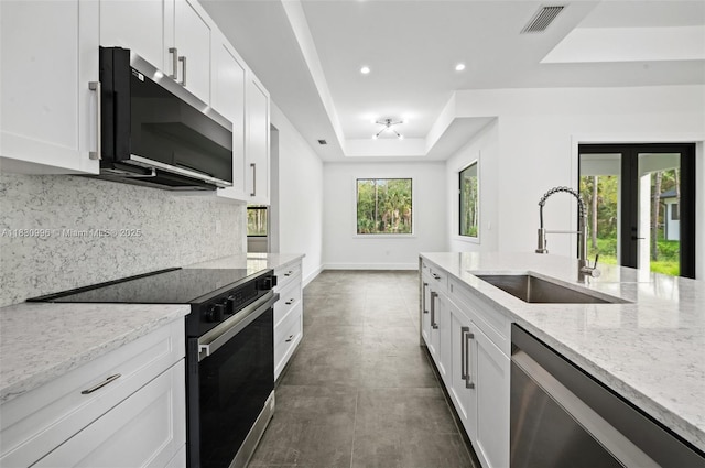 3324 NE 27, Naples, FL 34120 - kitchen featuring appliances with stainless steel finishes, a tray ceiling, tasteful backsplash, recessed lighting, and light stone countertops