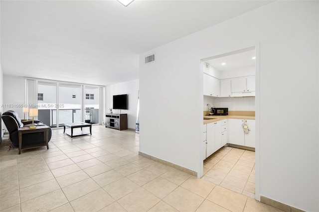 1200 W Ave Unit 1419, Miami Beach, FL 33139 - kitchen featuring light tile patterned floors, white cabinets, light countertops, open floor plan, and black microwave