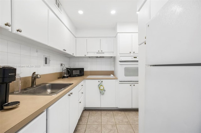 1200 W Ave Unit 1419, Miami Beach, FL 33139 - kitchen with white appliances, backsplash, under cabinet range hood, white cabinetry, and light countertops