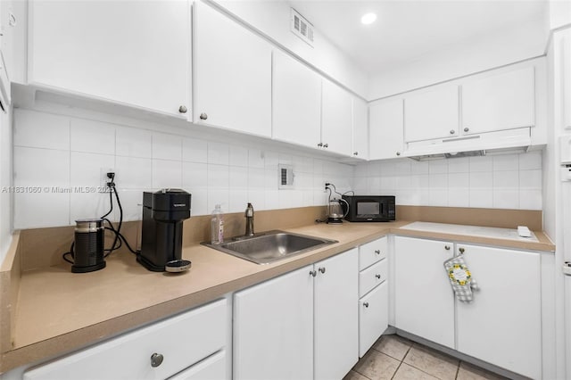 1200 W Ave Unit 1419, Miami Beach, FL 33139 - kitchen with under cabinet range hood, black microwave, decorative backsplash, and white cabinets