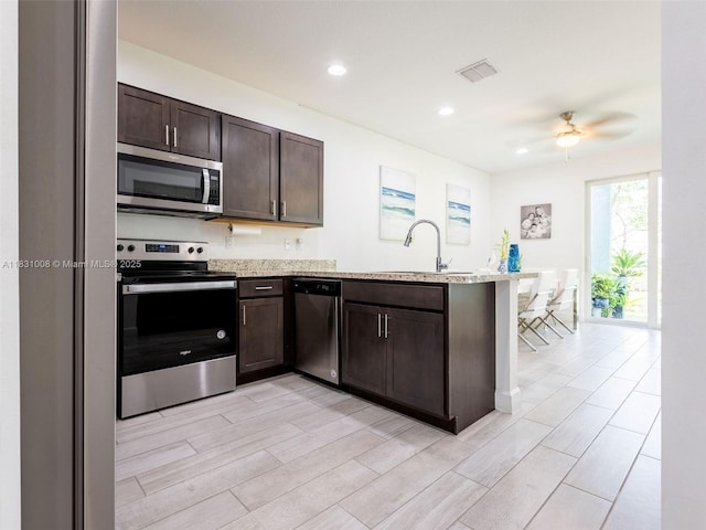 4923 NW 48th Ter, Tamarac, FL 33319 - kitchen featuring stainless steel appliances, a peninsula, a ceiling fan, dark brown cabinets, and wood finish floors
