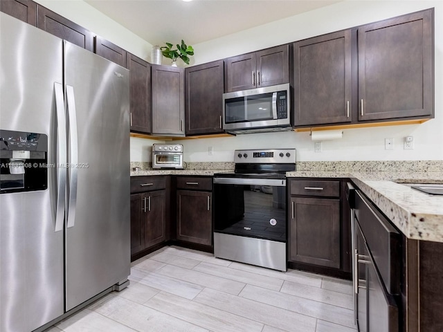 4923 NW 48th Ter, Tamarac, FL 33319 - kitchen featuring appliances with stainless steel finishes, dark brown cabinets, and light stone countertops