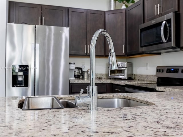 4923 NW 48th Ter, Tamarac, FL 33319 - kitchen featuring stainless steel appliances, dark brown cabinetry, and light stone countertops