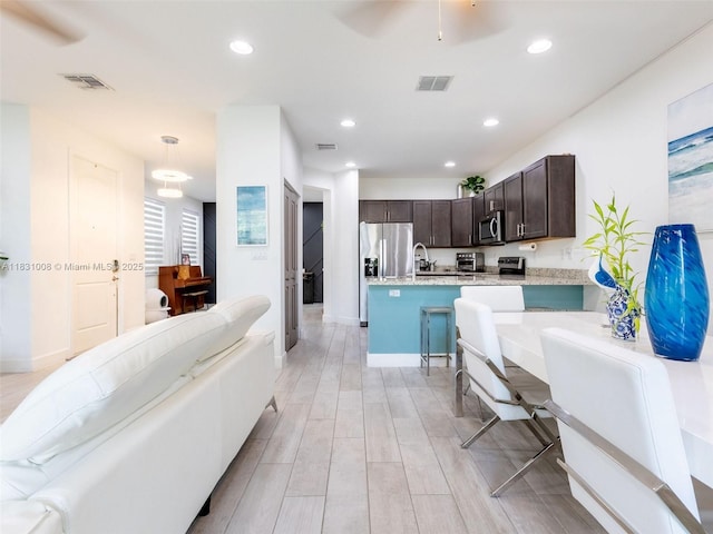 4923 NW 48th Ter, Tamarac, FL 33319 - kitchen with dark brown cabinetry, appliances with stainless steel finishes, light wood-style flooring, recessed lighting, and open floor plan