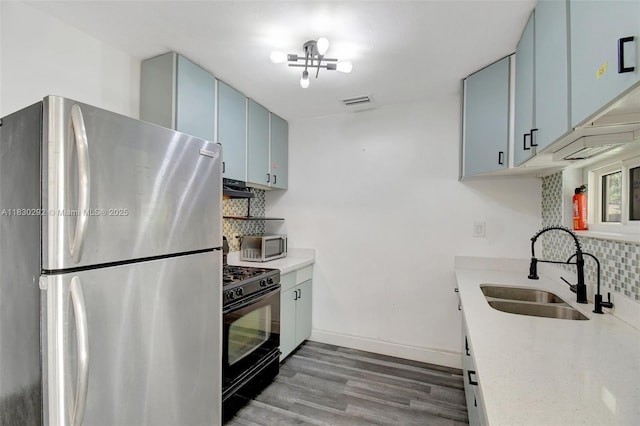 4917 SW 43rd Ter, Dania Beach, FL 33314 - kitchen featuring stainless steel appliances, backsplash, wood finished floors, blue cabinetry, and light countertops