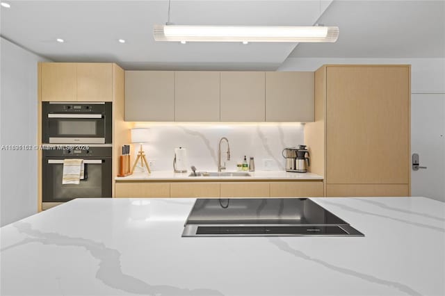 2301 Collins Ave Unit 407, Miami Beach, FL 33139 - kitchen with cooktop, light stone countertops, light brown cabinetry, cream cabinets, and decorative backsplash