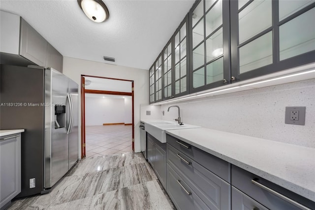15235 SW 99th Ct, Miami, FL 33157 - kitchen featuring appliances with stainless steel finishes, gray cabinetry, glass insert cabinets, a textured ceiling, and light stone countertops