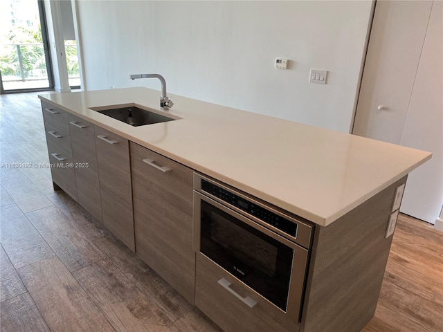 650 NE 32nd St Unit 802, Miami, FL 33137 - kitchen with modern cabinets, wood finished floors, a center island with sink, and light countertops