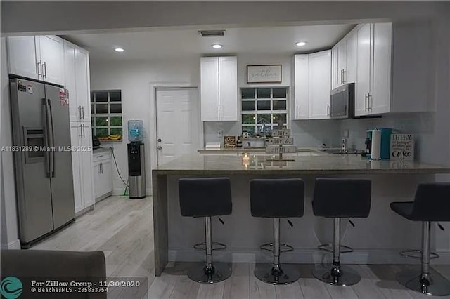 771 E 35th St, Hialeah, FL 33013 - kitchen with appliances with stainless steel finishes, a peninsula, white cabinets, a kitchen breakfast bar, and recessed lighting