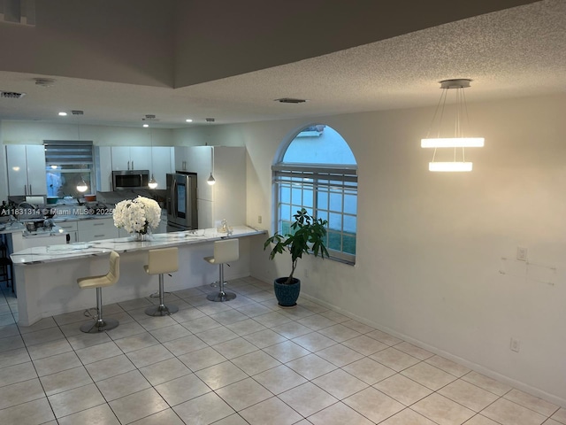 15271 NW 6th Ct, Pembroke Pines, FL 33028 - kitchen with appliances with stainless steel finishes, light tile patterned flooring, a kitchen breakfast bar, pendant lighting, and a peninsula