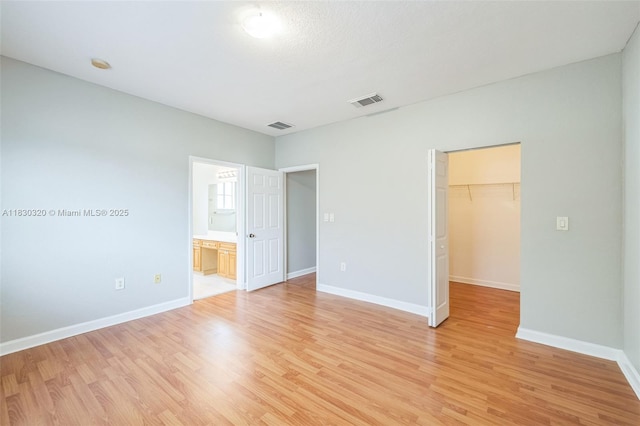 3156 NE 4th St, Homestead, FL 33033 - unfurnished bedroom with a walk in closet, light wood-style floors, a closet, and connected bathroom