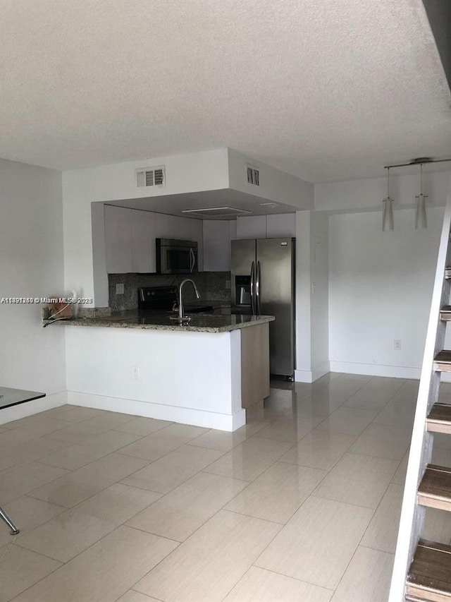 8670 NW 6th Ln Unit 4-208, Miami, FL 33126 - kitchen with stainless steel appliances, a textured ceiling, a peninsula, backsplash, and dark stone countertops