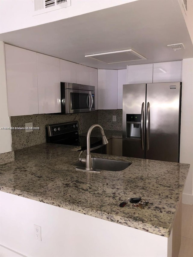 8670 NW 6th Ln Unit 4-208, Miami, FL 33126 - kitchen with stainless steel appliances, a peninsula, white cabinetry, and tasteful backsplash