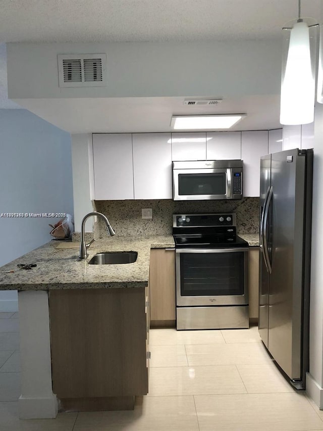 8670 NW 6th Ln Unit 4-208, Miami, FL 33126 - kitchen with stainless steel appliances, a peninsula, light stone countertops, light tile patterned flooring, and tasteful backsplash