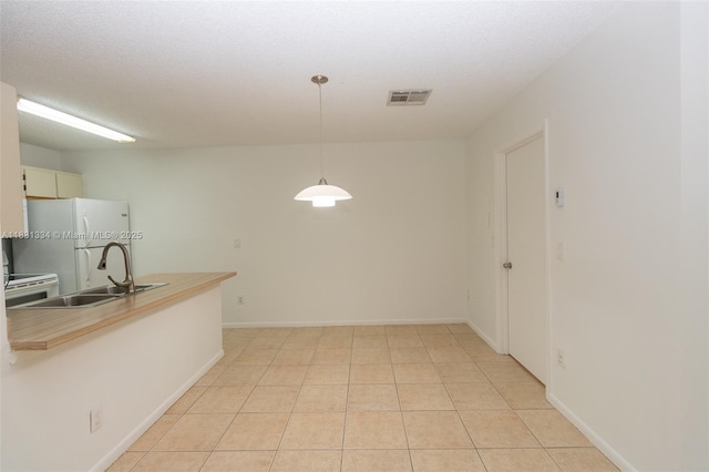 18328 NW 68th Ave Unit P, Hialeah, FL 33015 - kitchen featuring freestanding refrigerator, decorative light fixtures, a peninsula, light countertops, and light tile patterned floors