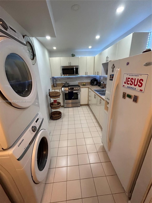 8251 NW 8th St Unit 214, Miami, FL 33126 - kitchen featuring appliances with stainless steel finishes, estacked washer and dryer, white cabinets, light tile patterned flooring, and recessed lighting