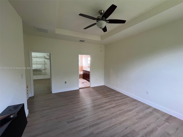 738 SE 37th Pl, Homestead, FL 33033 - unfurnished bedroom featuring a tray ceiling, dark wood finished floors, ensuite bath, a walk in closet, and ceiling fan