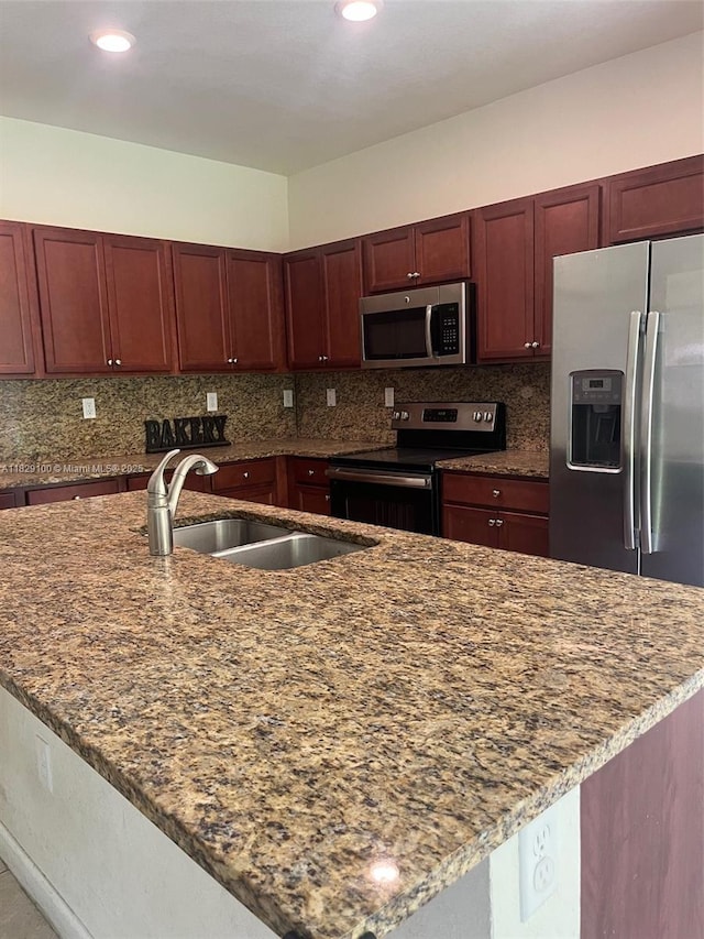 738 SE 37th Pl, Homestead, FL 33033 - kitchen with appliances with stainless steel finishes, dark stone counters, tasteful backsplash, a center island with sink, and reddish brown cabinets