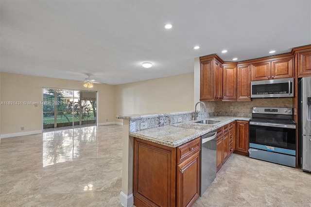 219 NE 14th Ave Unit 101, Hallandale Beach, FL 33009 - kitchen with appliances with stainless steel finishes, a peninsula, brown cabinets, light stone counters, and recessed lighting