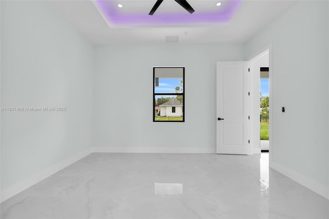 3209 45th St SW, Lehigh Acres, FL 33976 - empty room featuring a tray ceiling, marble finish floors, healthy amount of natural light, a ceiling fan, and recessed lighting