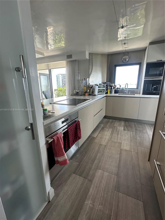 2333 Brickell Ave Unit 901, Miami, FL 33129 - kitchen with stainless steel oven, black electric stovetop, wood finished floors, white cabinetry, and light countertops