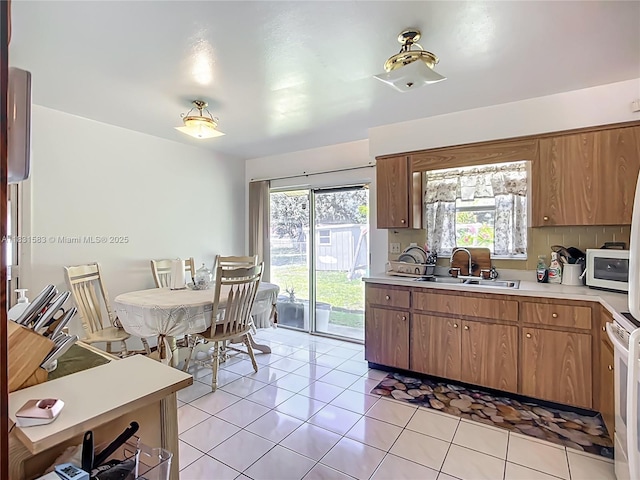 1206 E 27th St, Bradenton, FL 34208 - kitchen featuring light countertops, light tile patterned floors, brown cabinets, and white microwave