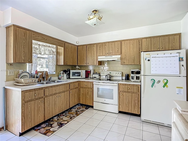 1206 E 27th St, Bradenton, FL 34208 - kitchen with white appliances, under cabinet range hood, light countertops, and decorative backsplash
