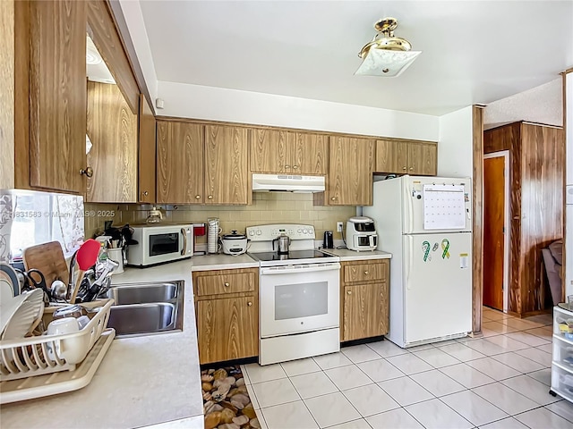 1206 E 27th St, Bradenton, FL 34208 - kitchen featuring white appliances, under cabinet range hood, light countertops, backsplash, and brown cabinets