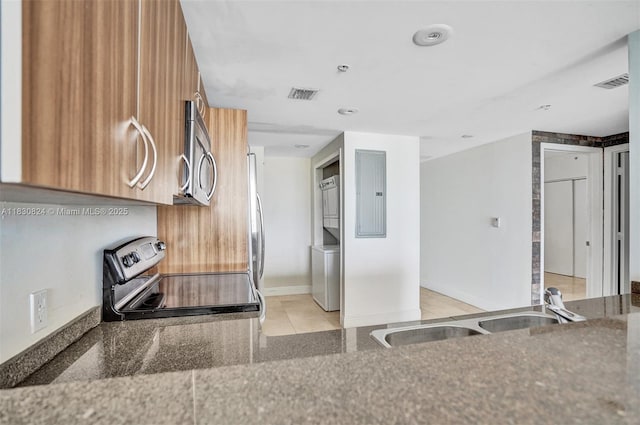 6305 Indian Creek Dr Unit 3B, Miami Beach, FL 33141 - kitchen with range with electric cooktop, stainless steel microwave, brown cabinets, electric panel, and dark stone countertops