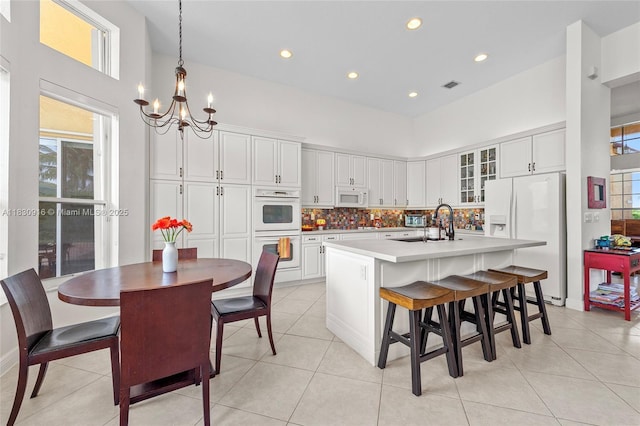 19442 SW 39th St, Miramar, FL 33029 - kitchen featuring white appliances, a chandelier, a kitchen island with sink, healthy amount of natural light, and a towering ceiling