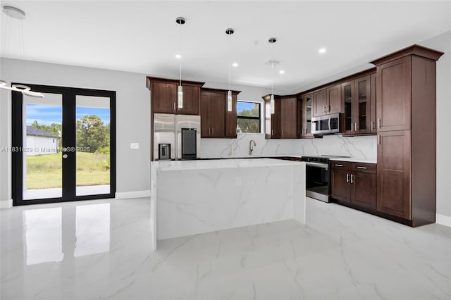2505 40th, Lehigh Acres, FL 33976 - kitchen featuring stainless steel appliances, a kitchen island, glass insert cabinets, hanging light fixtures, and dark brown cabinetry