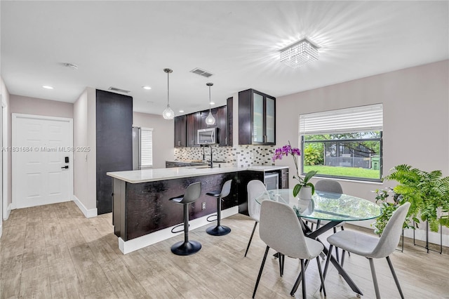 10527 NW 6th St, Pembroke Pines, FL 33026 - kitchen featuring stainless steel microwave, dark brown cabinets, light countertops, a peninsula, and light wood-type flooring