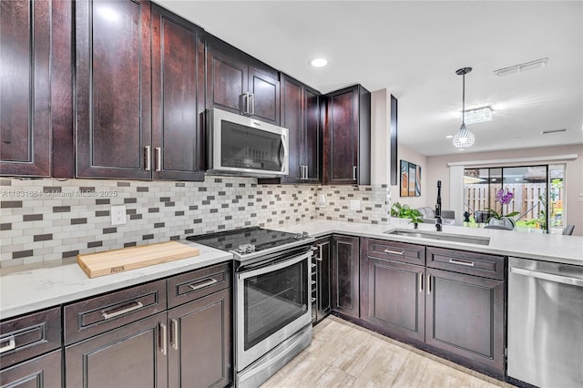 10527 NW 6th St, Pembroke Pines, FL 33026 - kitchen featuring stainless steel appliances, light wood-type flooring, light countertops, backsplash, and hanging light fixtures